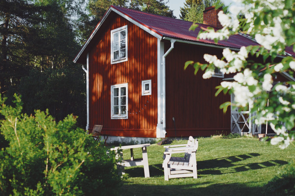 Ett rött hus med ett rött tak och en vit bänk.