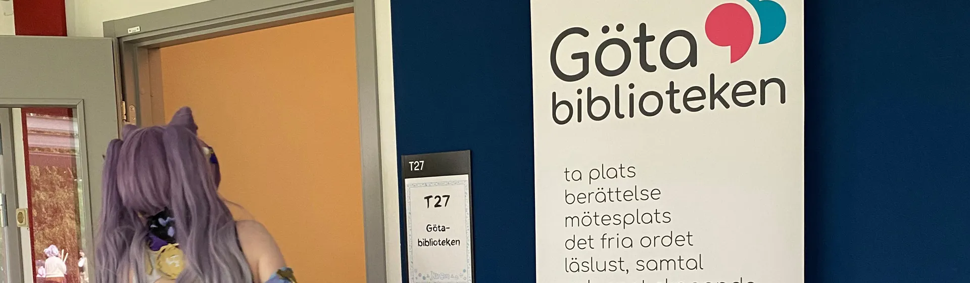 En kvinna i kostym som står framför en skylt.
