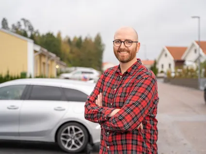 En man som står framför en parkerad bil.