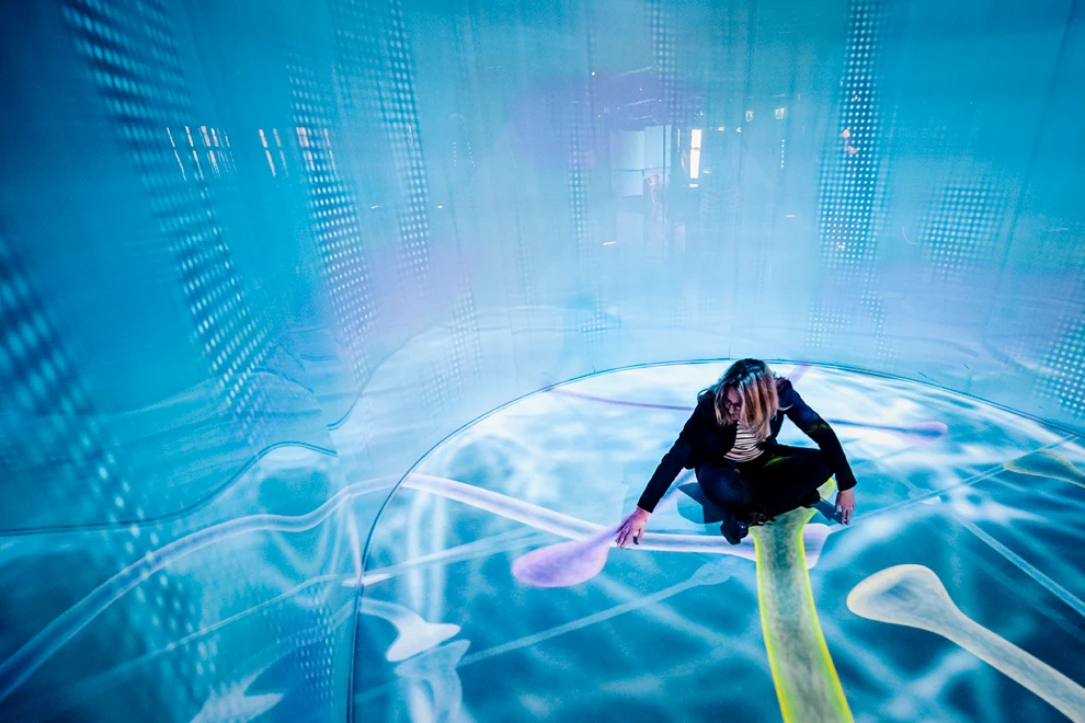 A woman in a black top is floating in a blue room.