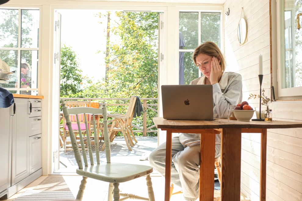 A woman sitting at a table using a laptop computer.