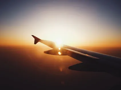 Solen går ner över ett flygplans vinge.