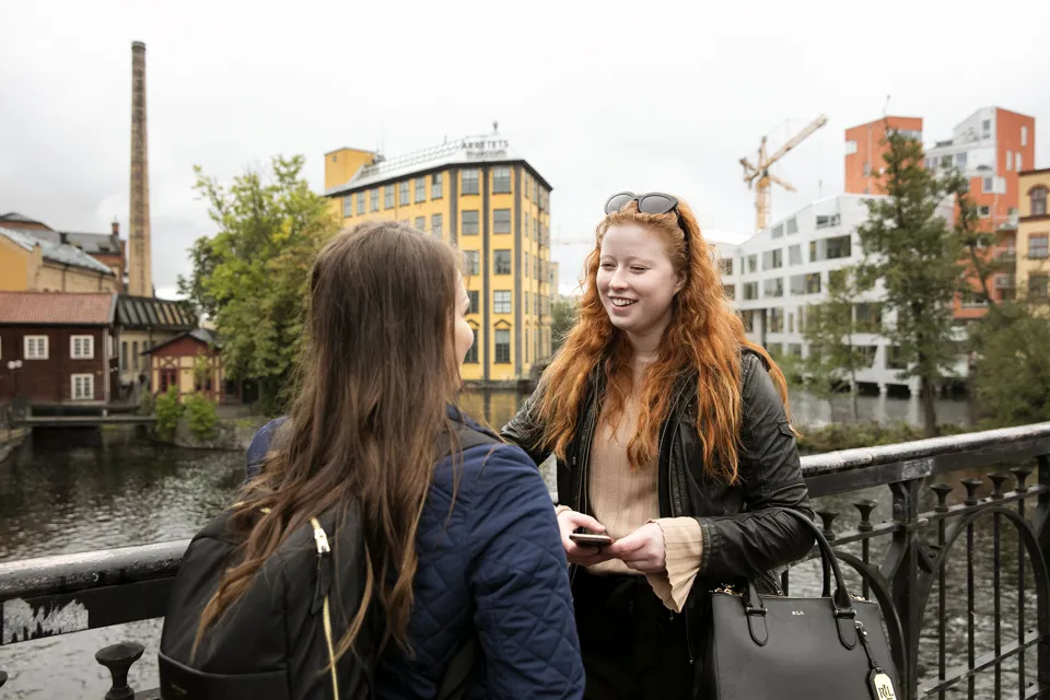 Två personer står mot ett staket vid strömmen inne i Norrköping